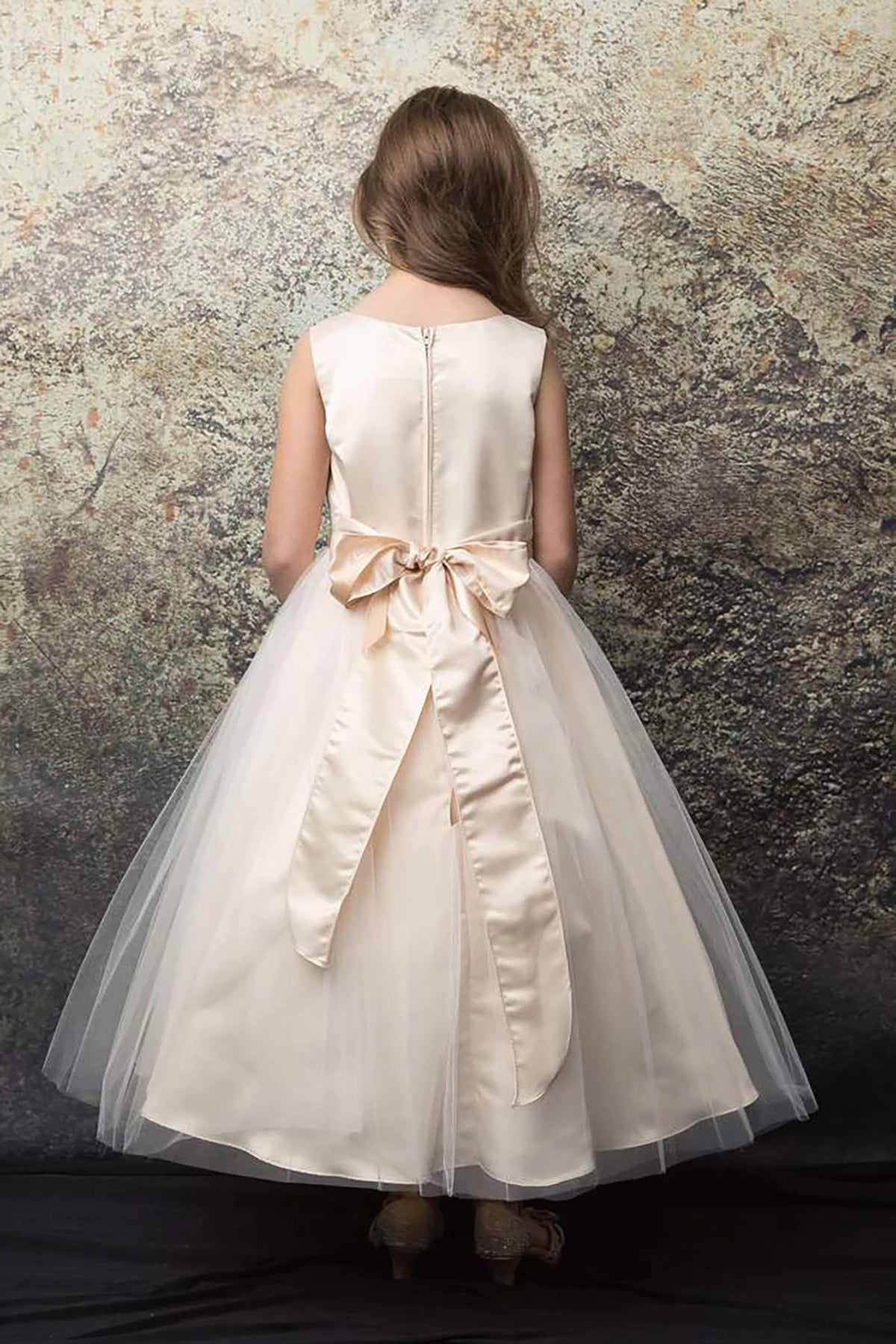 A champagne flower girl dress with a bow.