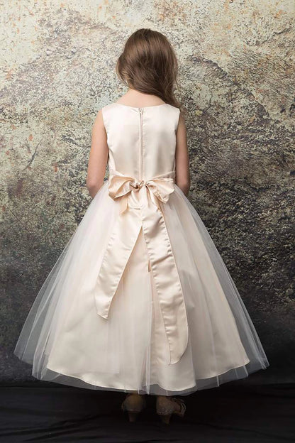 Decorative elements define a champagne flower girl dress with a bow.