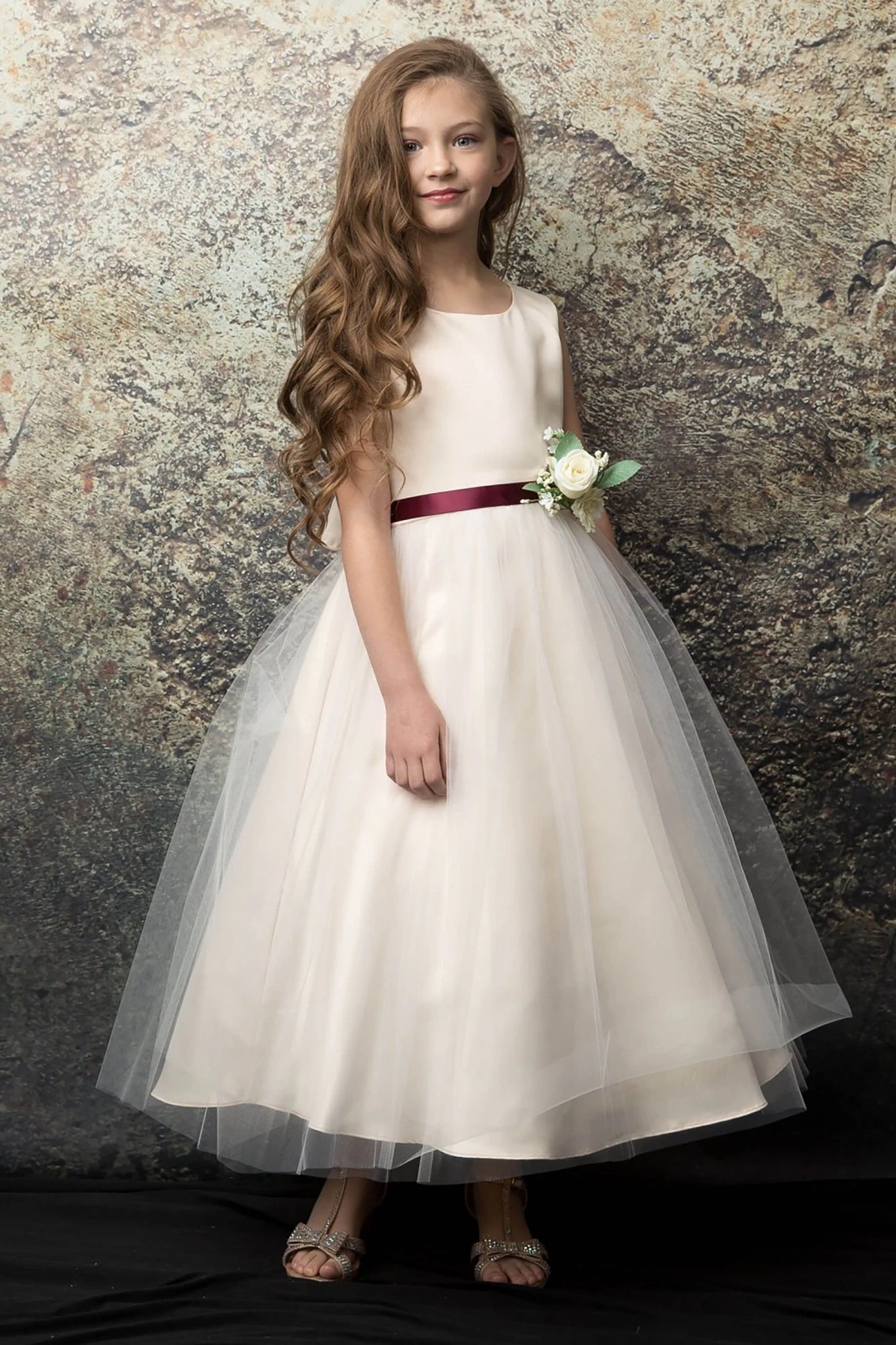 A champagne flower girl dress with a burgundy belt.
