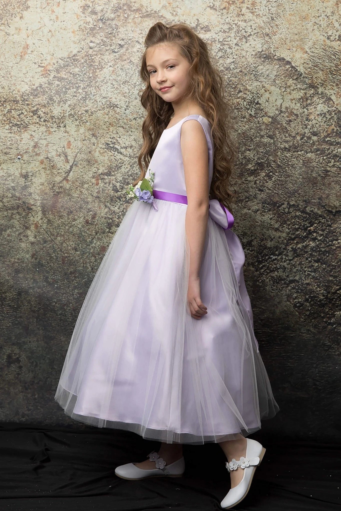 A lilac flower girl dress with a purple sash.