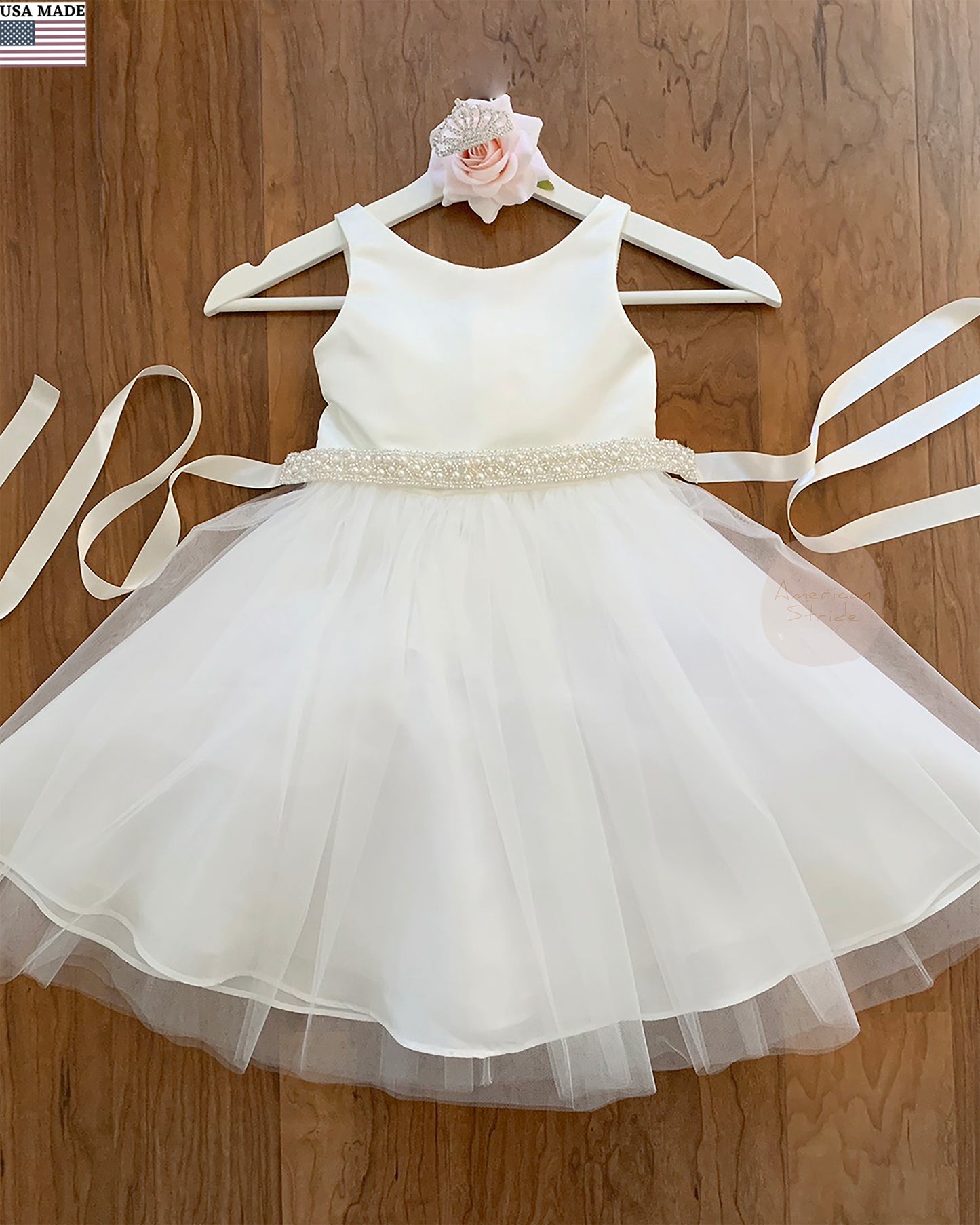 offwhite dress with ivory pearl sash on a wood background
