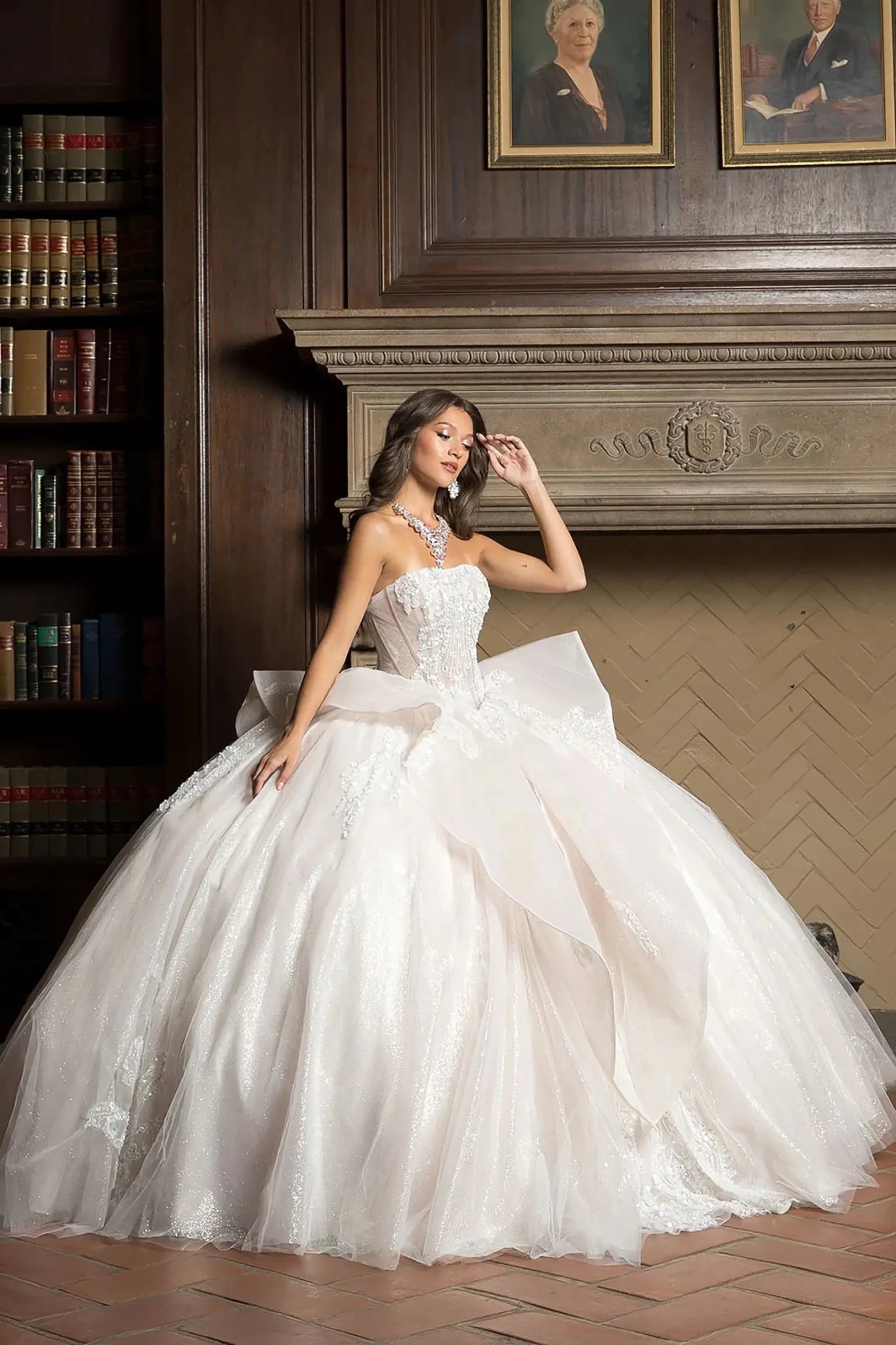 Woman in a white wedding dress sitting in a room with wooden paneling and bookshelves.
