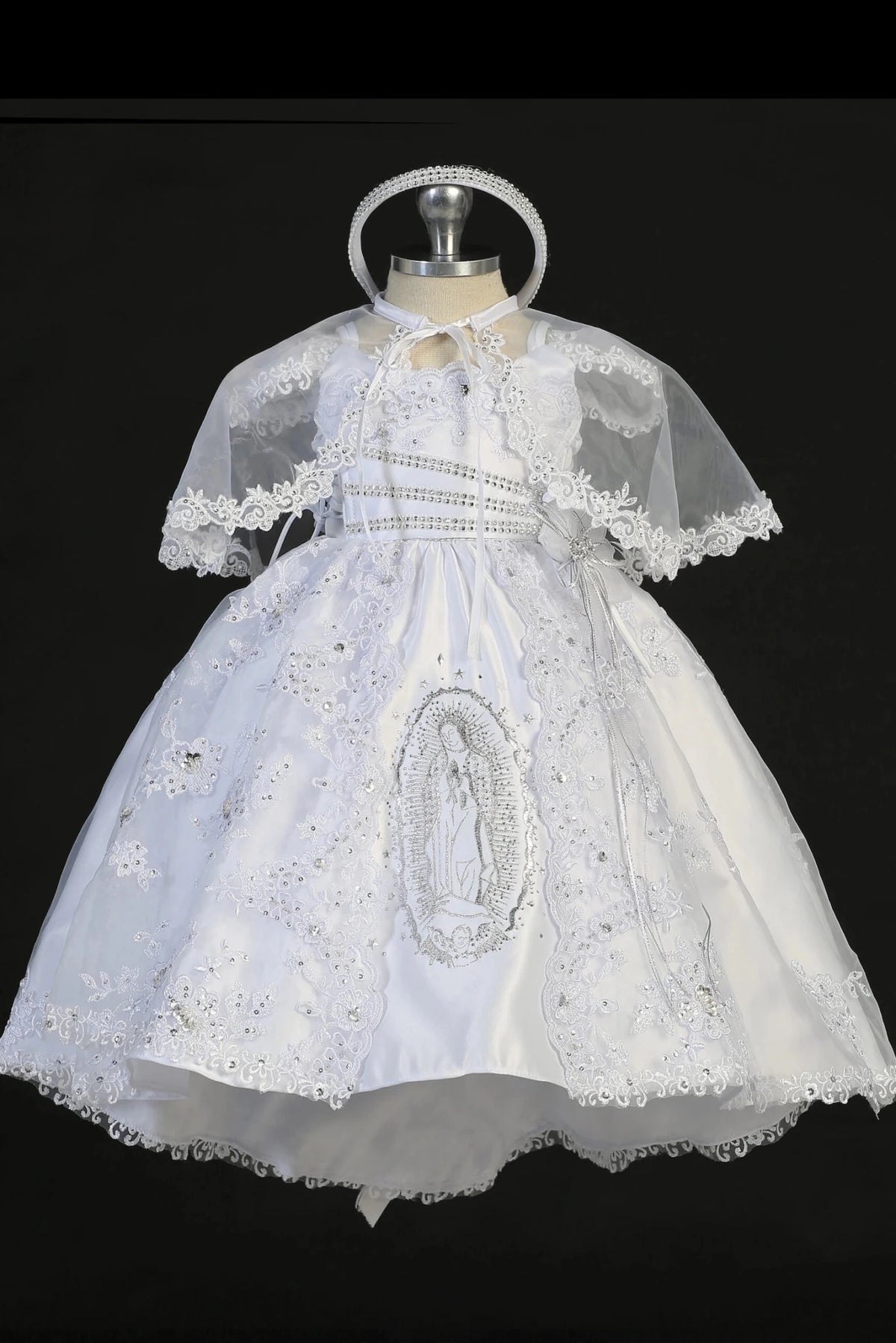 White baptism dress with lace bodice with rhinestone accents and a flower at the waist.