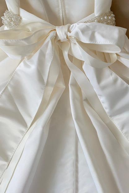 Close-up of a white dress with a large bow detail.