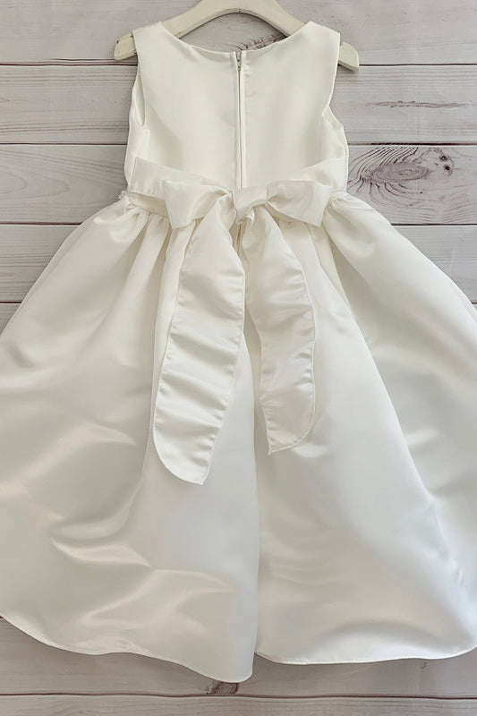 Ivory dress with a bow on a wooden surface