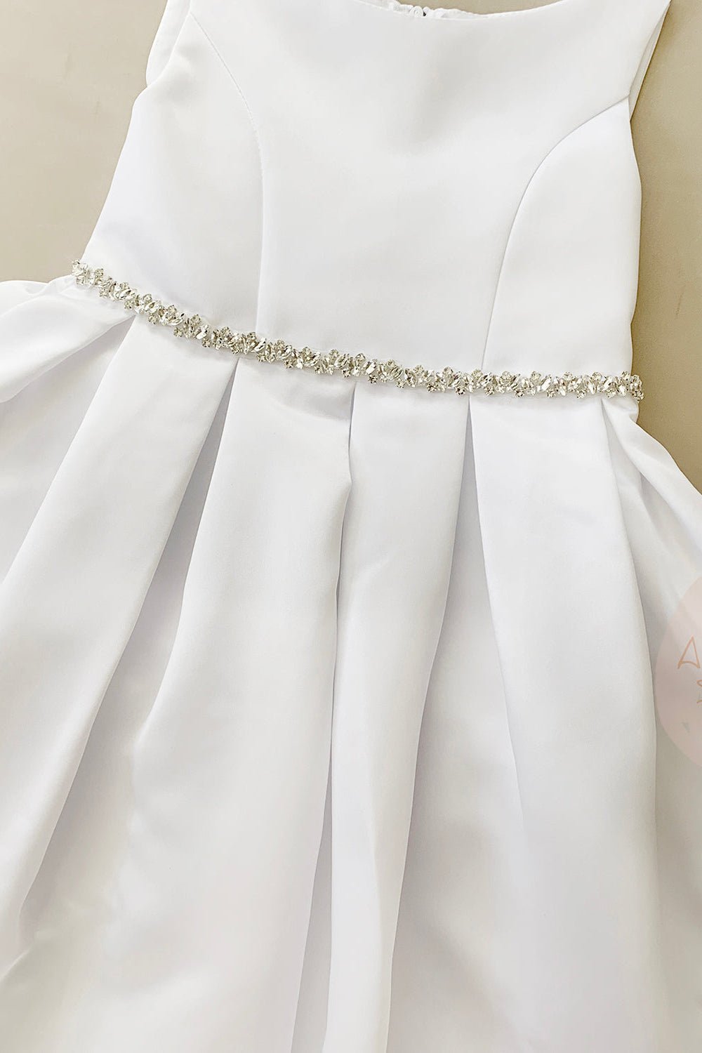 White dress with a decorative belt on a neutral background