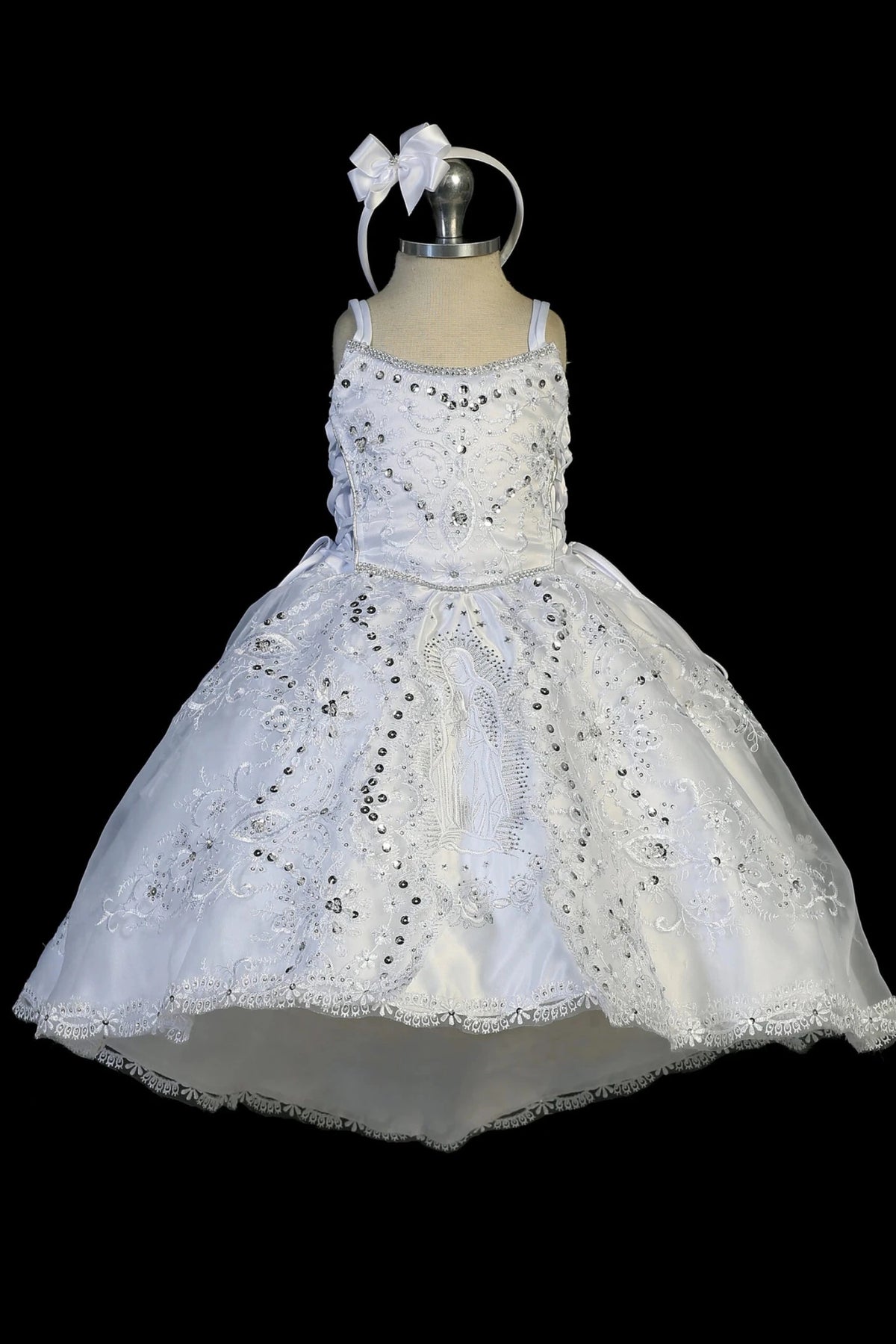 Detail of the white baptism dress showing Virgin Mary embroidery above a second ruffled skirt.