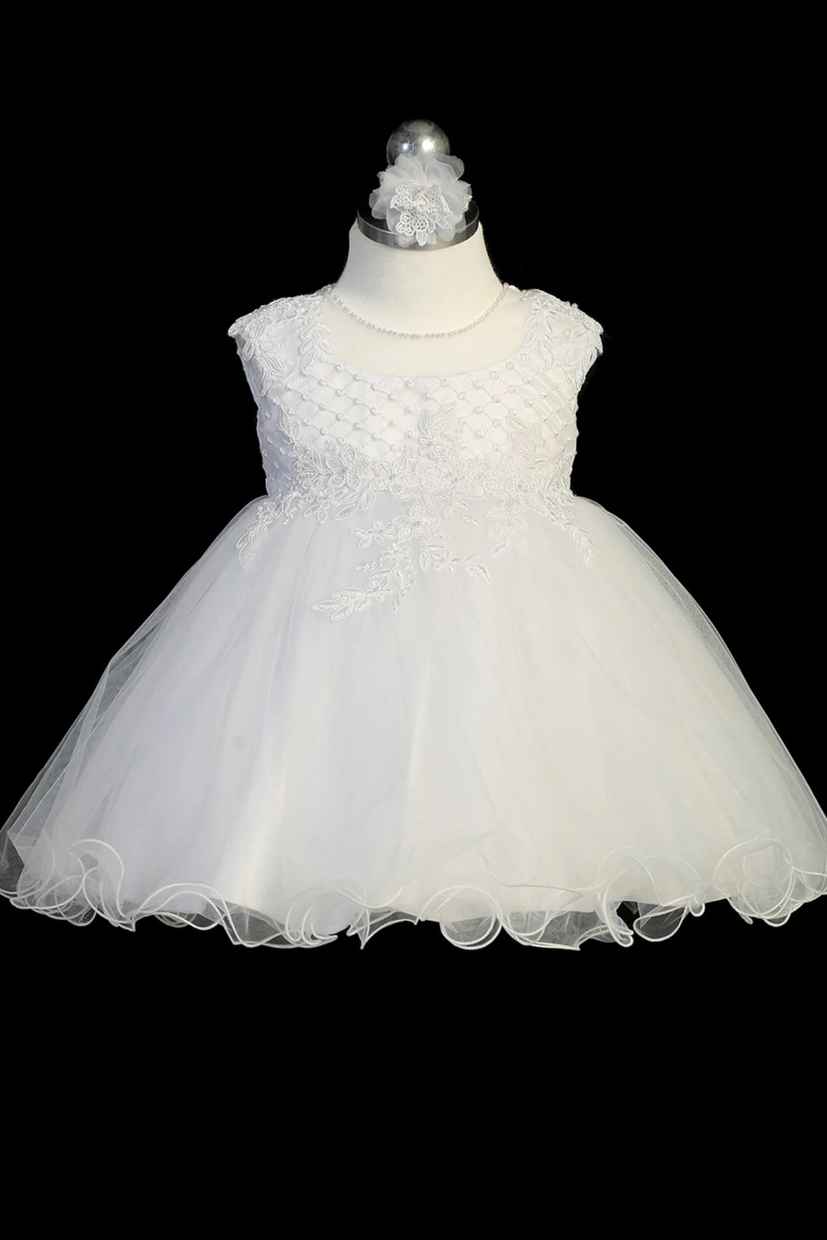 Detail of the white christening dress showing lace waist appliqué and a mesh overlay skirt.