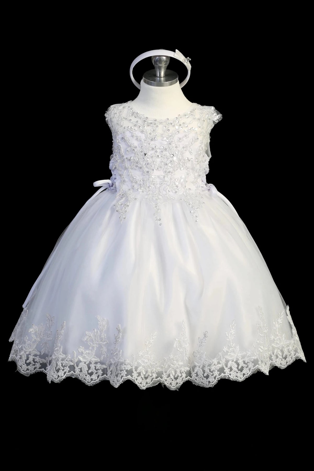 Detail of the white christening dress showing organza overlay skirt with a lace hem.