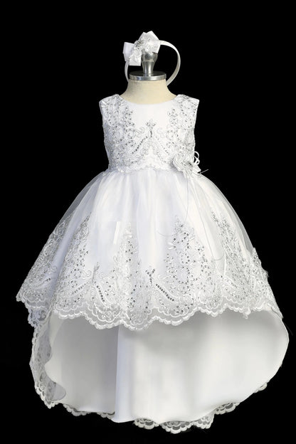 Detail of the white baptism dress showing high-low organza skirt with a lace-appliqué hem.