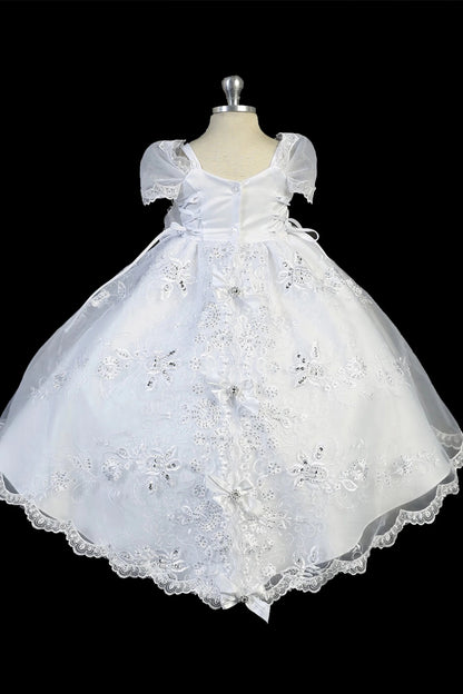 Detail of the white baptism dress showing Virgin Mary embroidery on the split organza skirt.