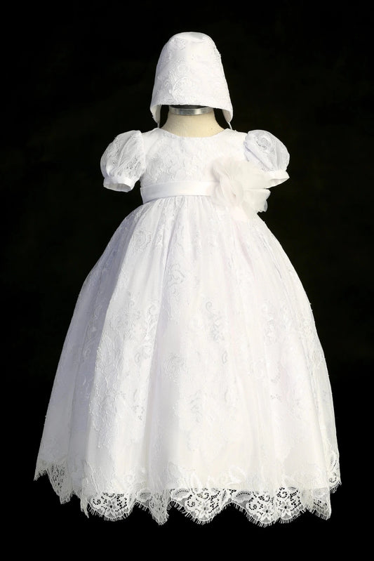 White christening dress with puff-sleeved lace bodice and a satin waist sash.