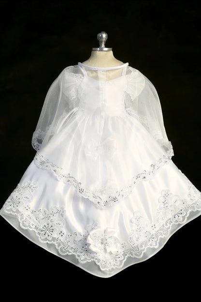 Detail of the white baptism dress showing split organza overlay above a Virgin Mary embroidered satin skirt.