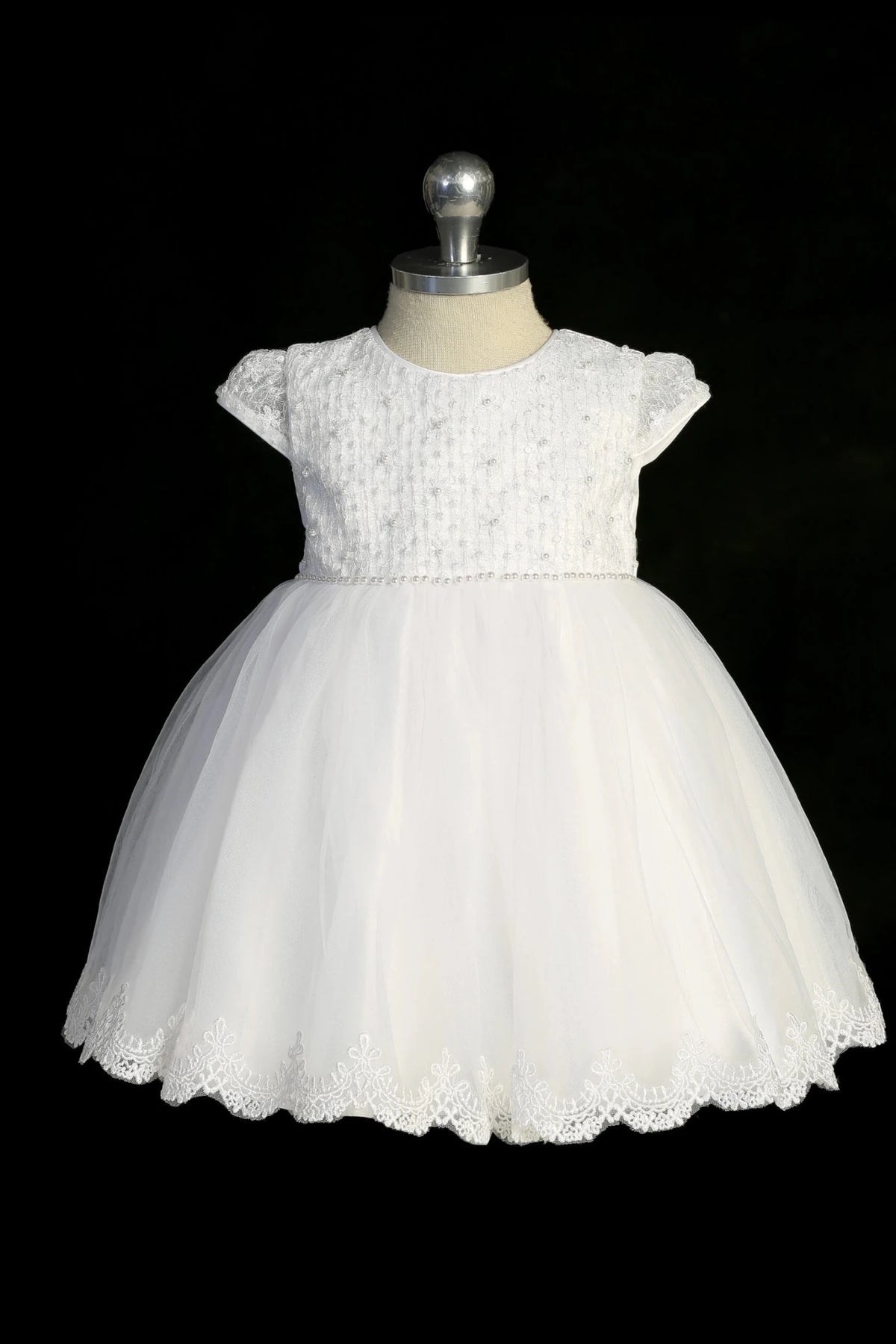 Detail of the white christening dress showing scalloped lace hem.