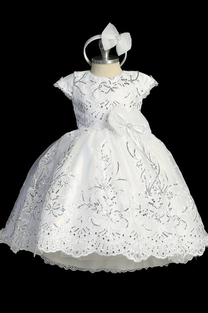 Detail of the white christening dress showing scalloped organza lace skirt and bow accents.