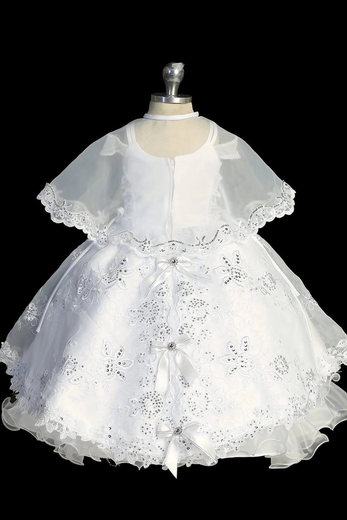 Another view of the white baptism dress with cap-sleeved lace bodice and a removable waist brooch.