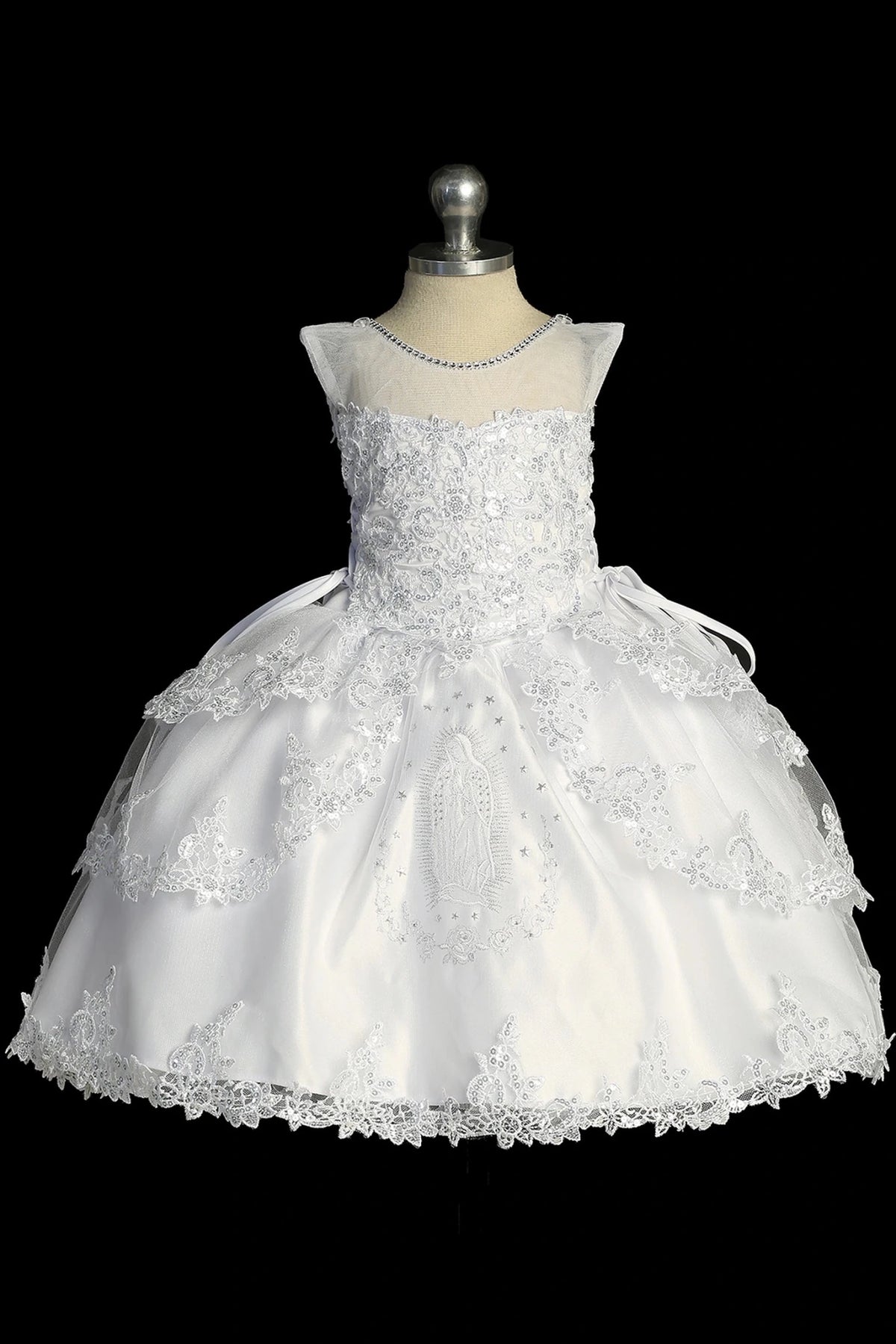 Detail of the white baptism dress showing Virgin Mary embroidery at the center of the skirt.