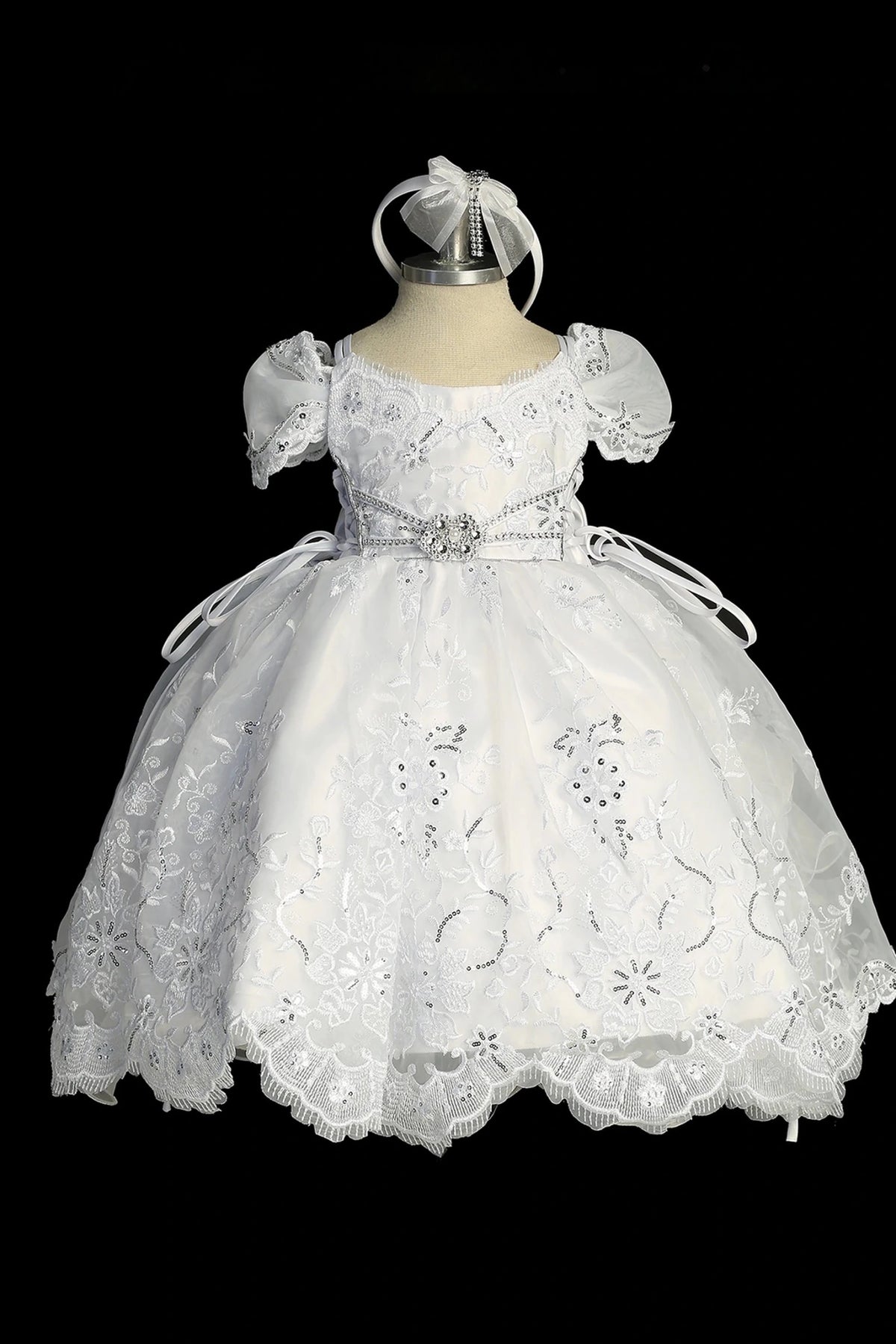 Detail of the white baptism dress showing scalloped hem with back ruffles and a large satin bow.