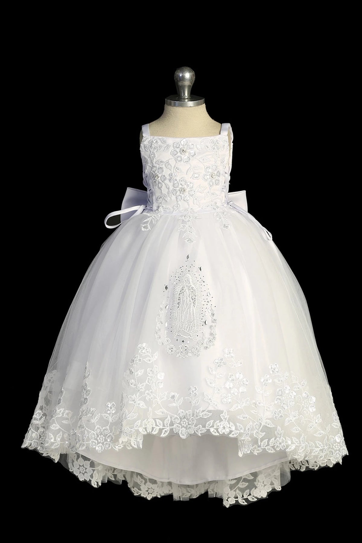 Detail of the white baptism dress showing high-low tulle skirt with lace and Virgin Mary embroidery.