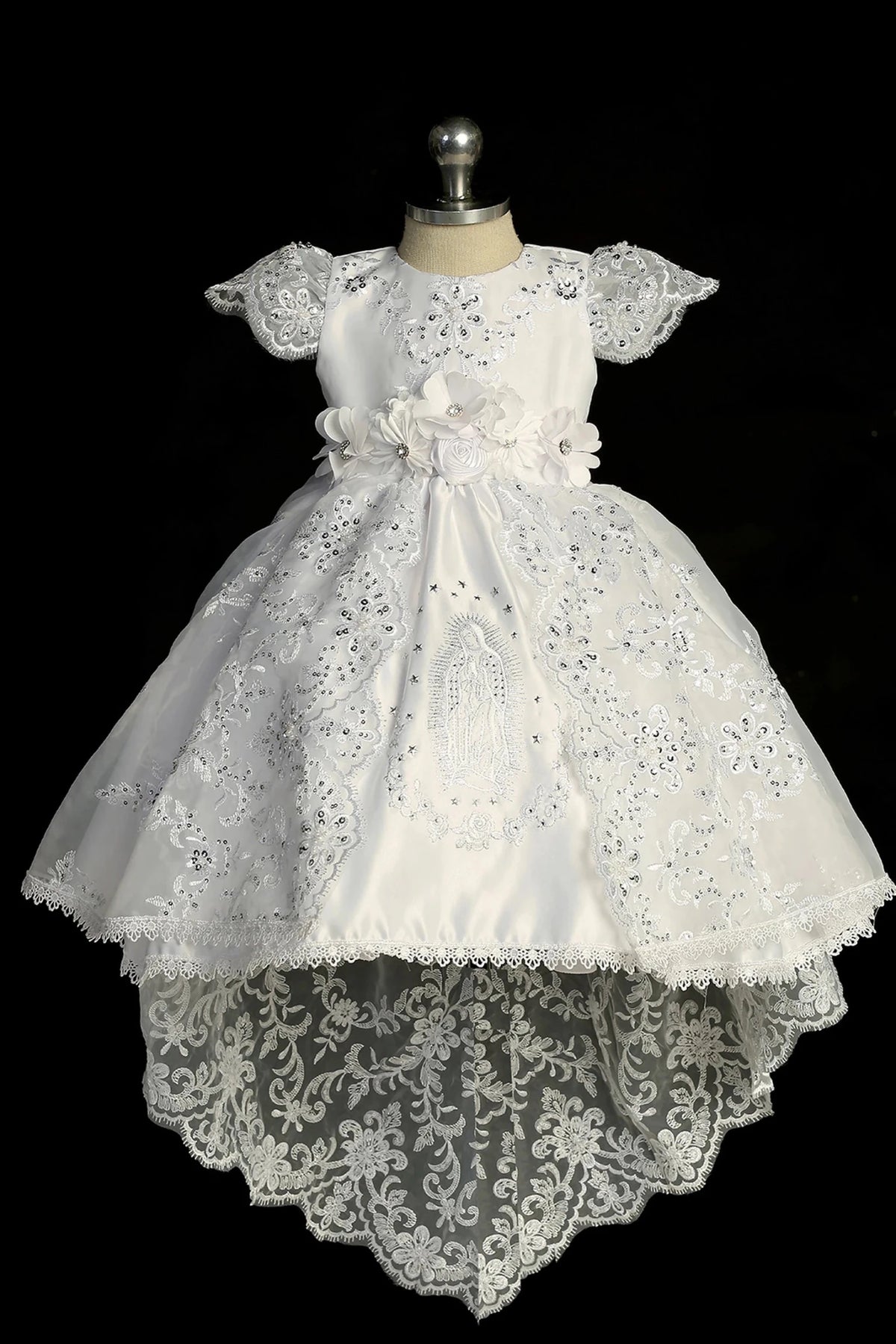 Detail of the white baptism dress showing Virgin Mary embroidery on the satin skirt.
