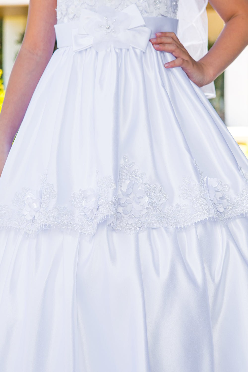 Close-up of white Satin Cap Sleeve communion dress with Beaded Skirt, Lace Details.