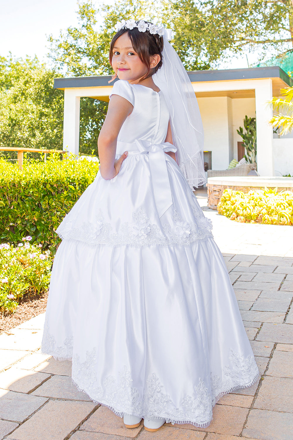 Elegant Illusion Top satin Cap Sleeve Embellished Skirt Communion Dress with Beads, Laces and Back Satin Sash - back view of girl wearing dress with hand on hip