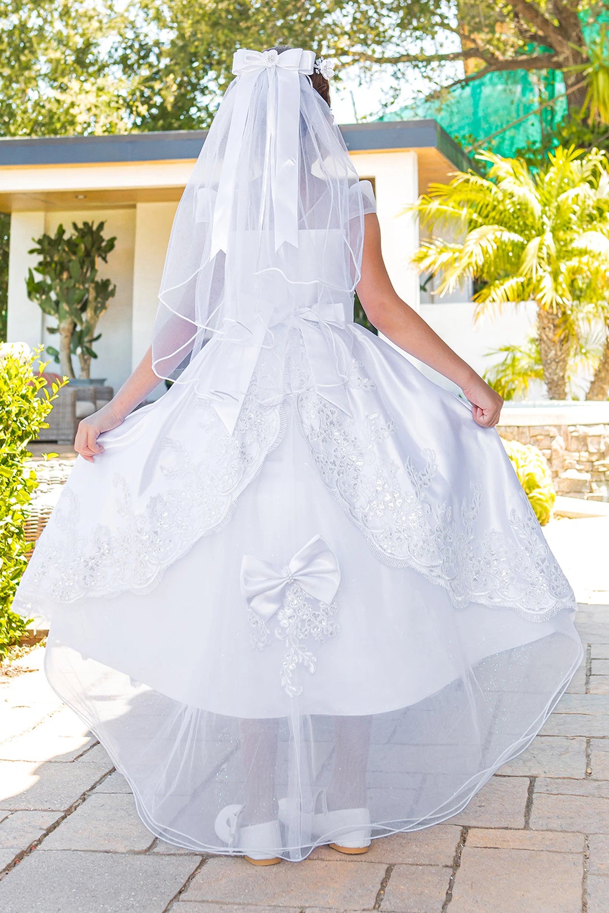 Back satin sash forms a broad bow on this White communion dress.