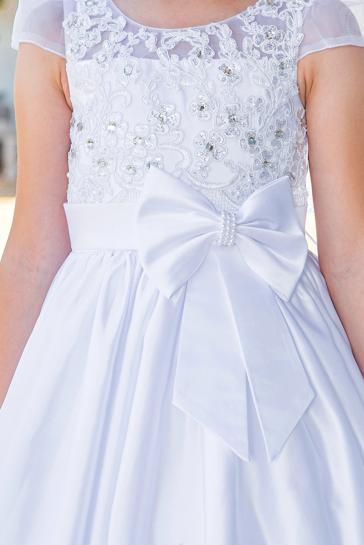 Rhinestone center accents the front satin bow of the White communion dress.