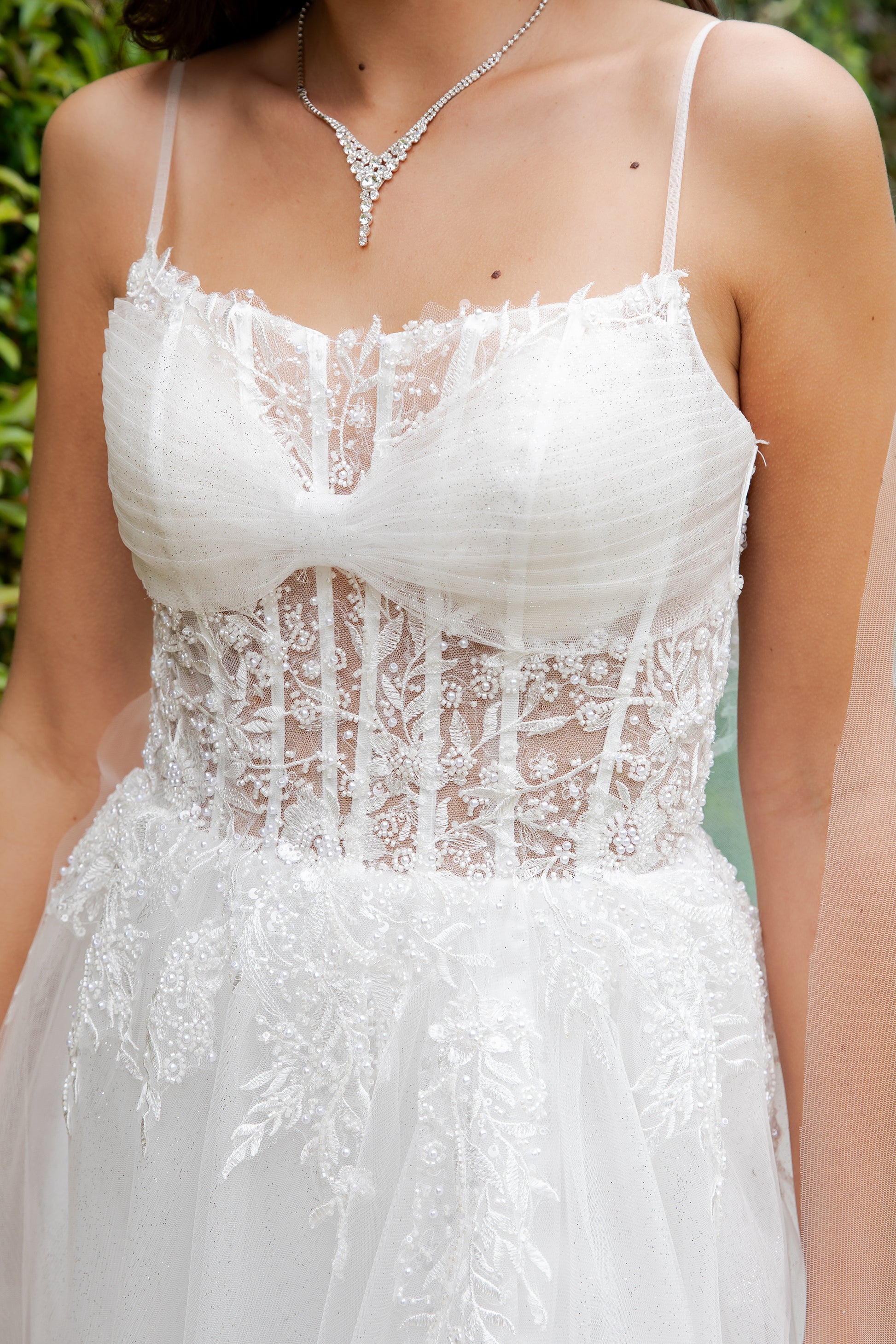 White lace dress with a close-up of the bodice against a blurred green background