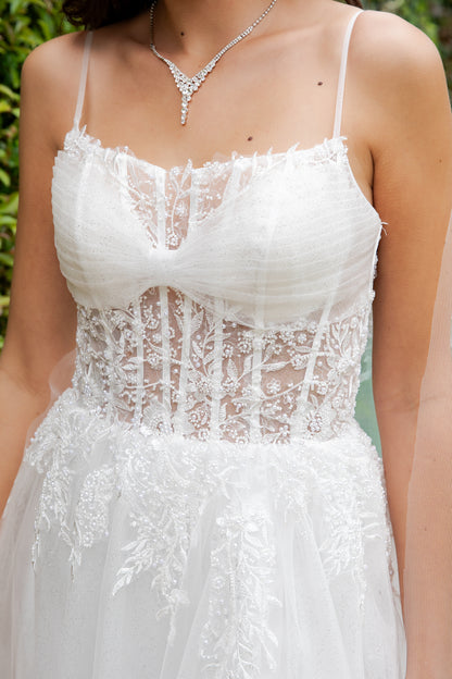 White lace dress with a close-up of the bodice against a blurred green background