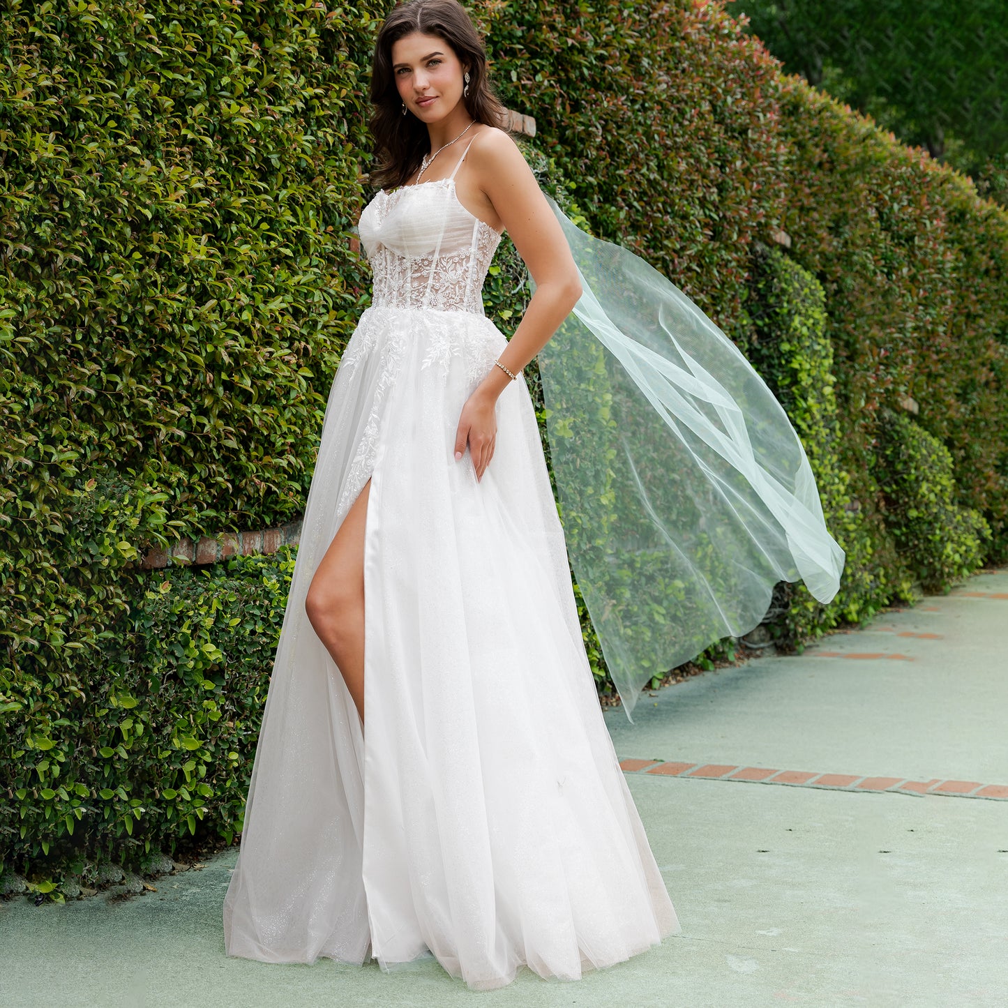 Woman in a white wedding dress with a green hedge background