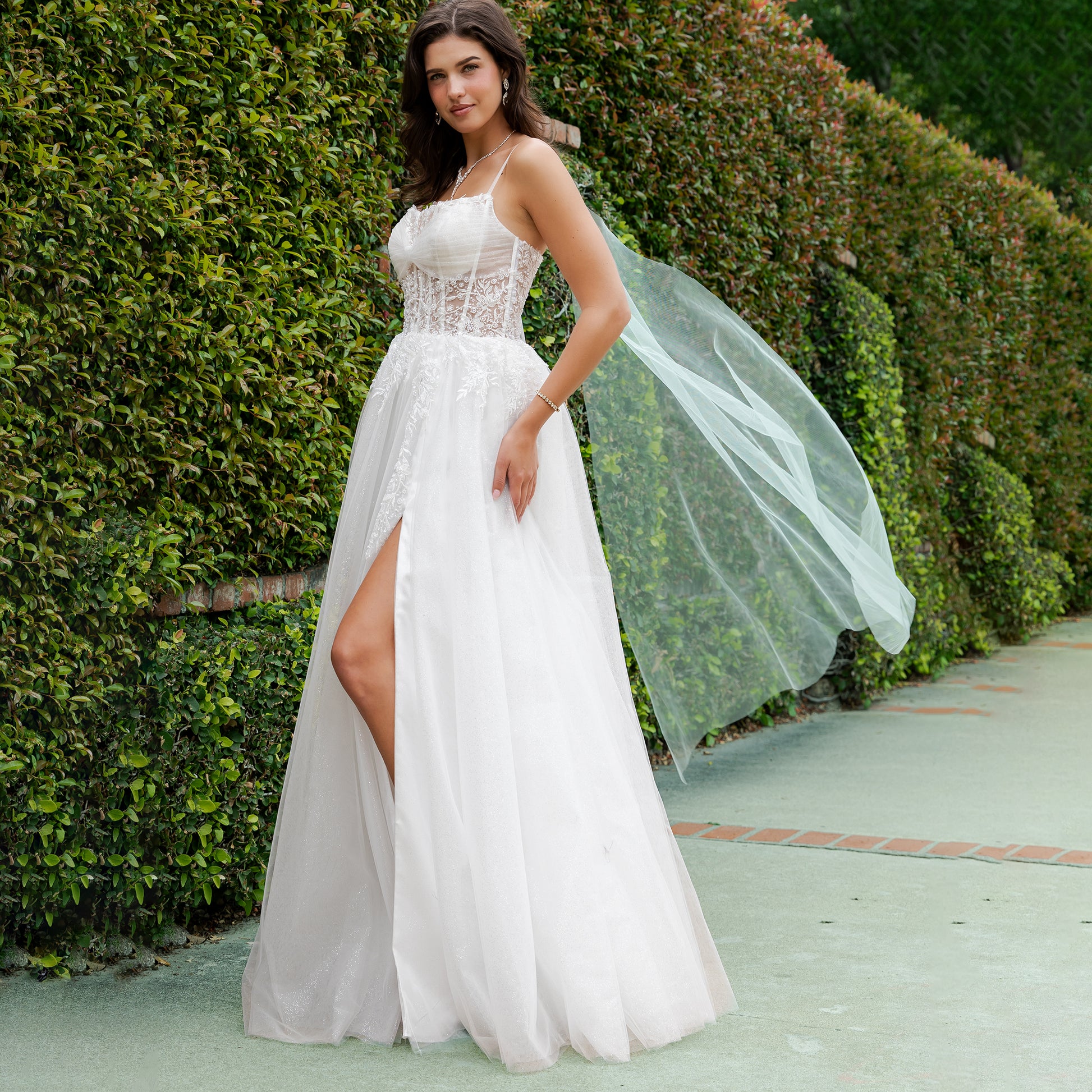 Woman in a white wedding dress with a green hedge background