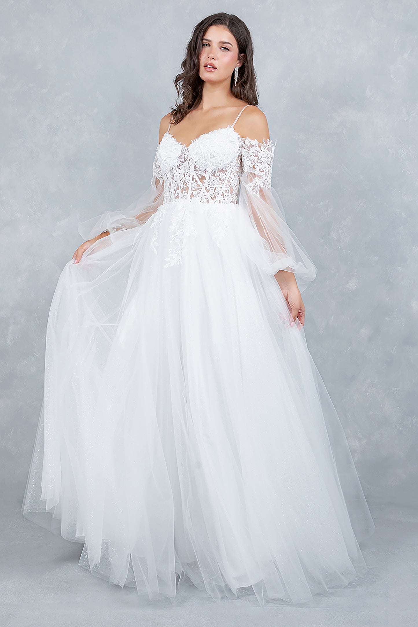 Woman wearing a white wedding dress with lace top and tulle skirt on a gray background