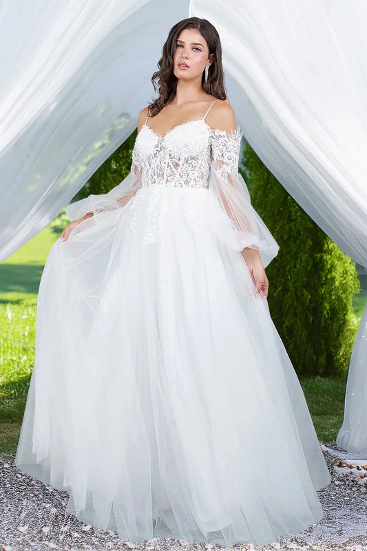 Woman in a white wedding dress with lace long sleeves standing outdoors with greenery in the background