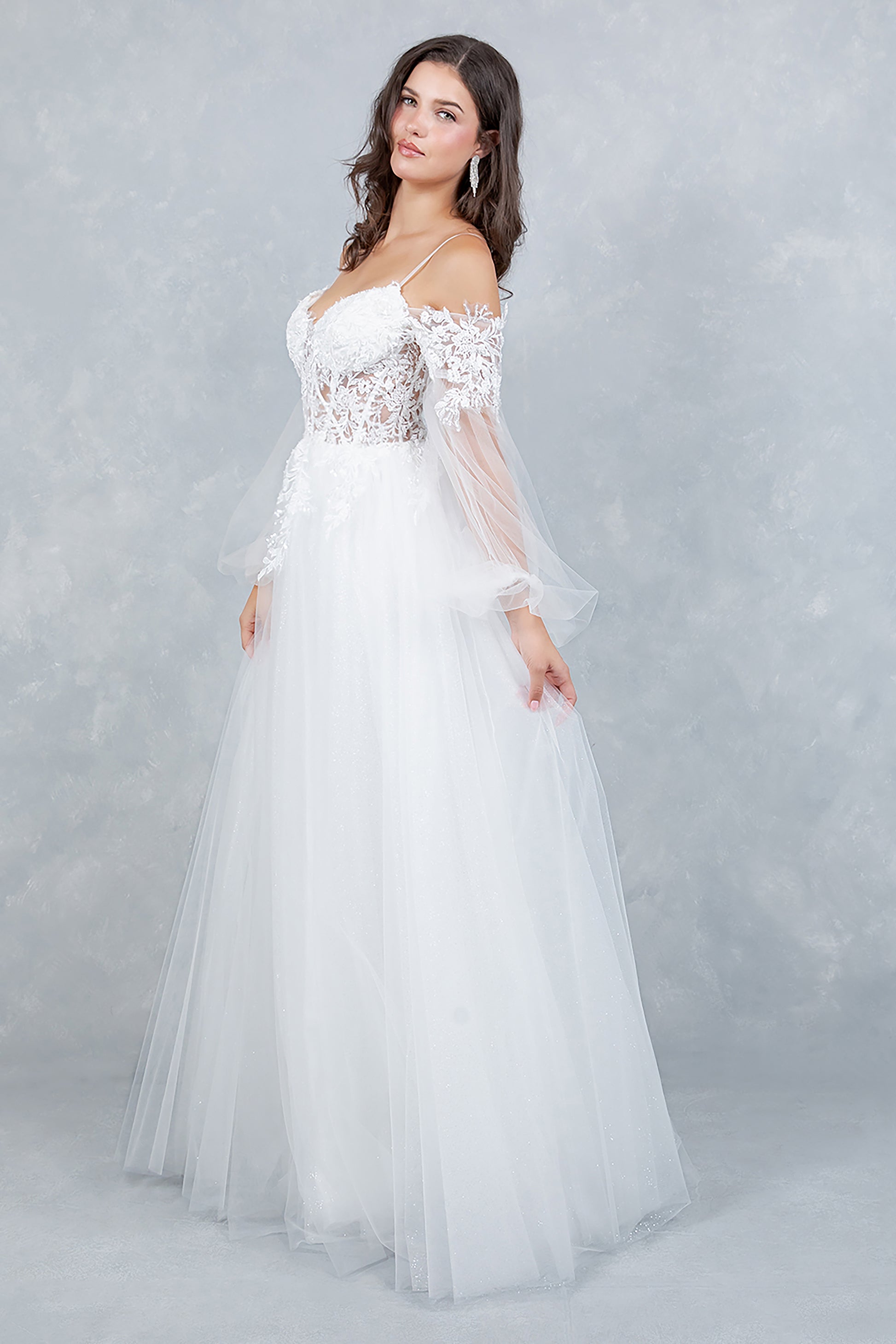 Woman wearing a white wedding dress with lace detailing on a light gray background