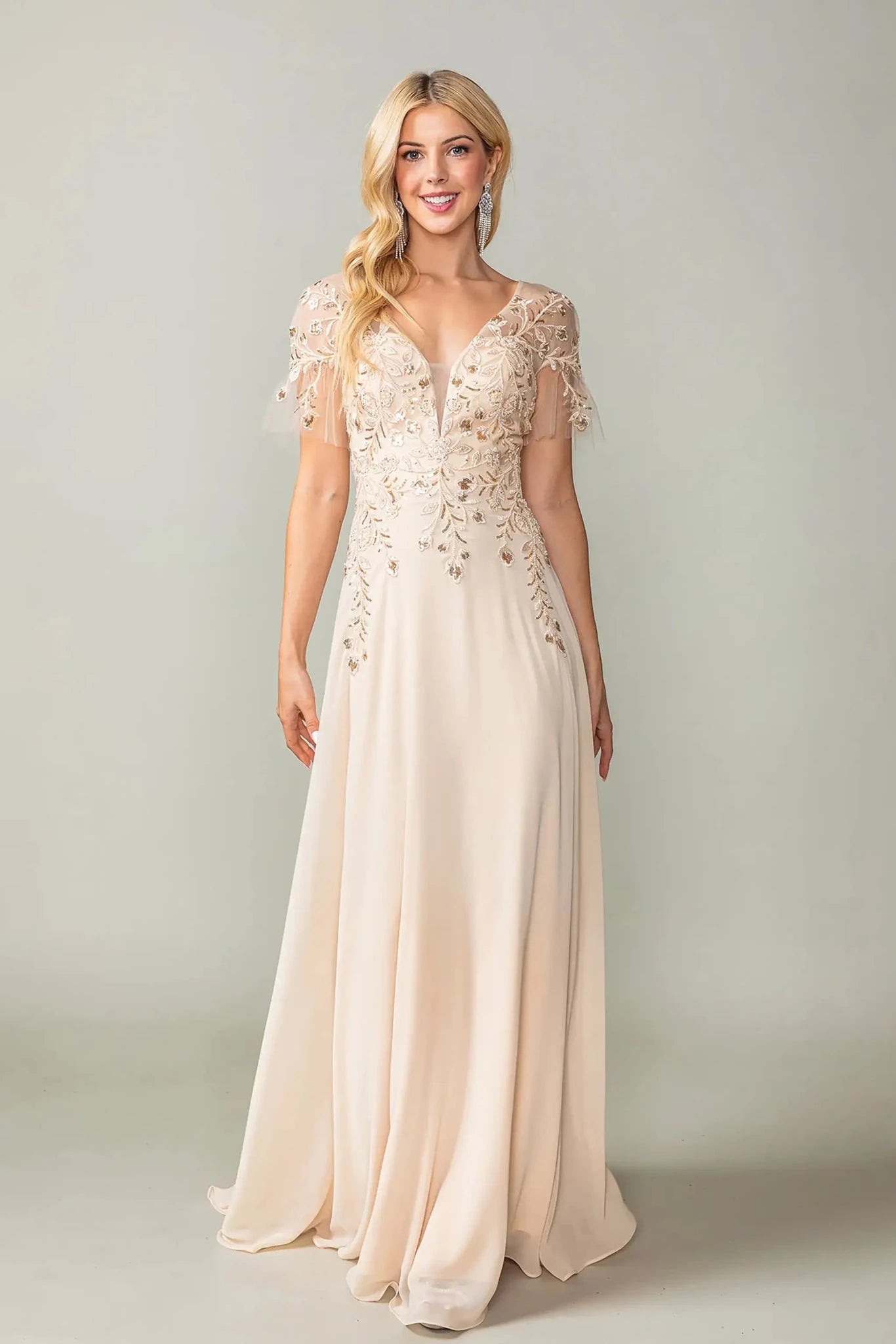 Woman in Champagne prom dress with applique and flutter sleeves.