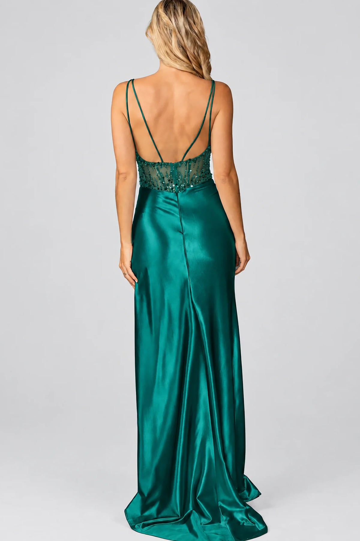floor-length emerald green satin gown from the back, featuring thin spaghetti straps, a lace-trimmed open back, and a full skirt