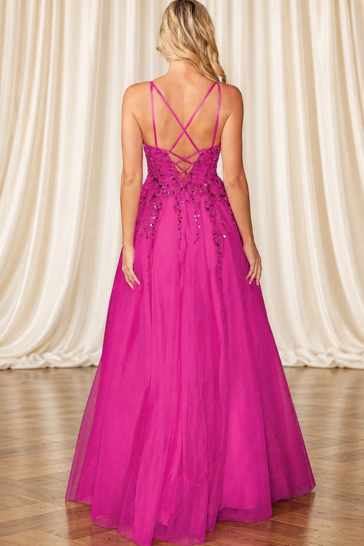 fuchsia pink formal gown with thin crisscross straps, a lace-up open back, and beaded embellishments on the bodice