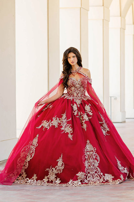 Quinceanera | Wine with Gold Embroidered Lace with Stunning Cape Quince Ballgown dress - front view of woman wearing dress standing in front of pillars