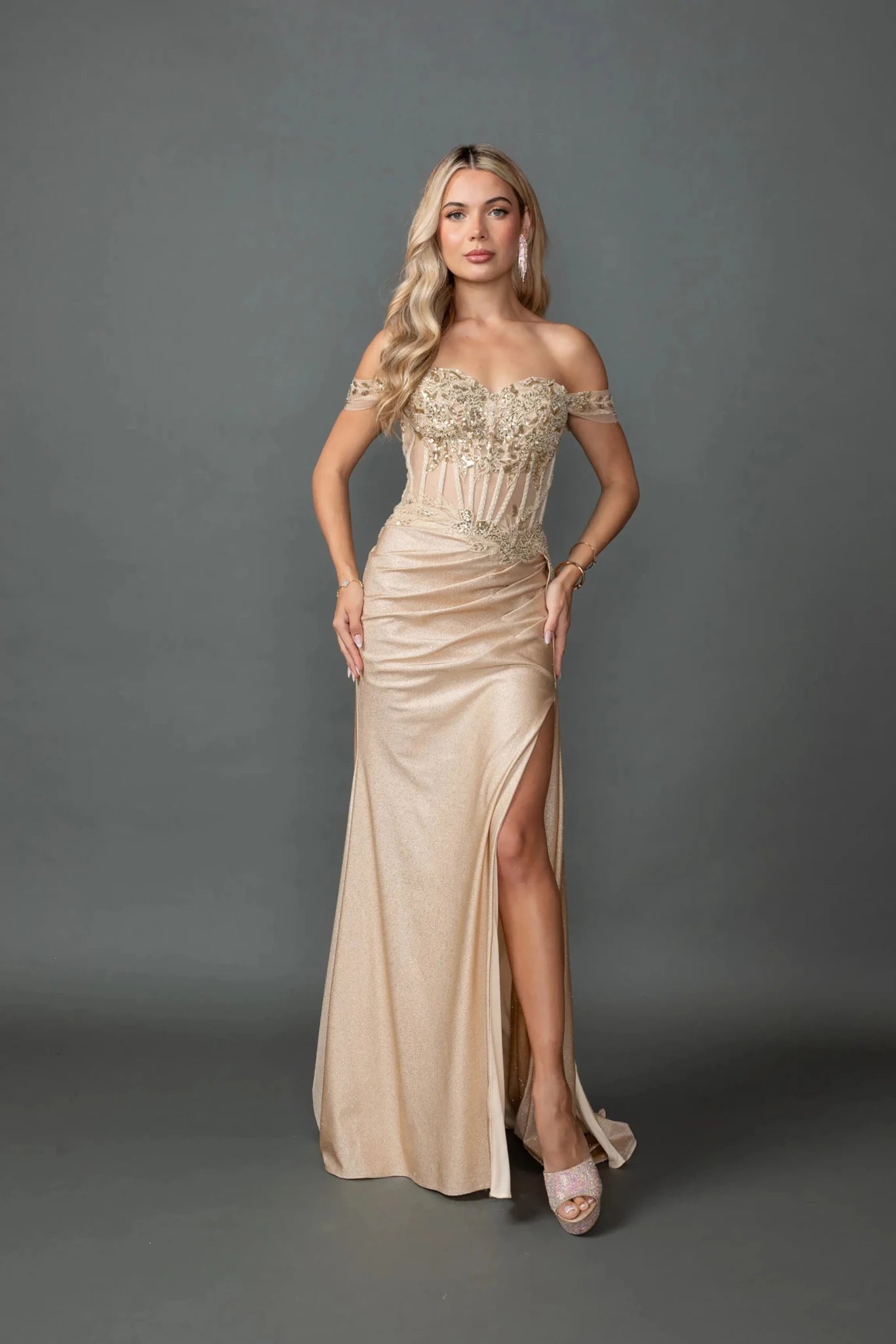 Woman in Gold off-shoulder glitter prom dress with corset and slit.