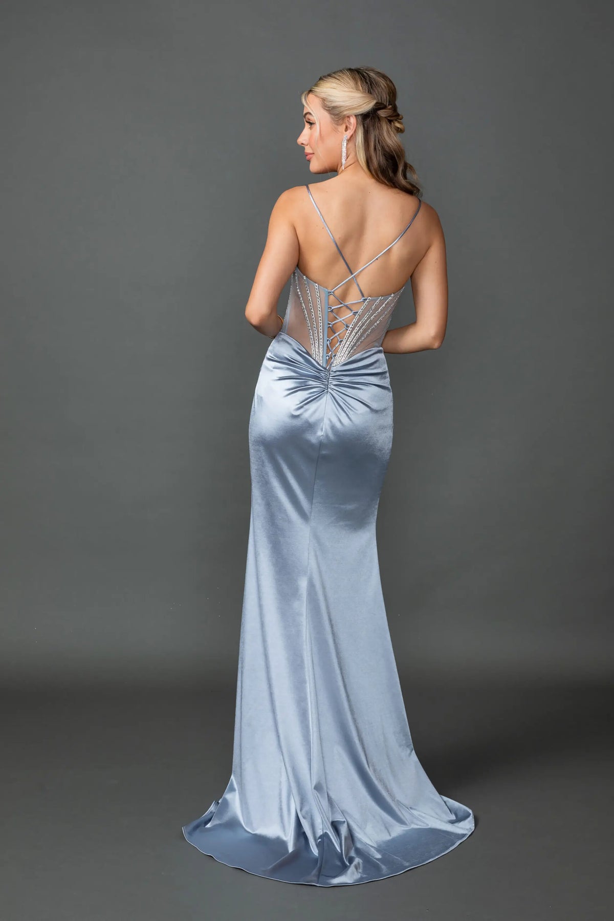 Revealing crisscross straps above its satin skirt, this Dusty Blue prom dress is shown from the back.