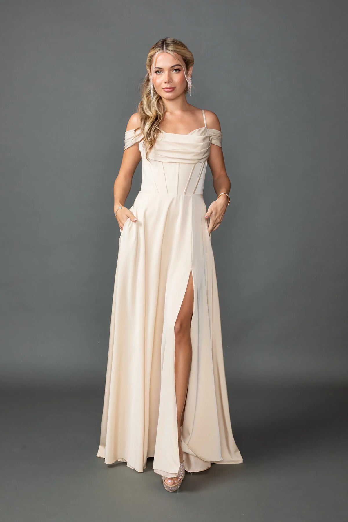 Showing a draped cowl neckline and high-slit skirt, this Champagne prom dress is shown in full view.
