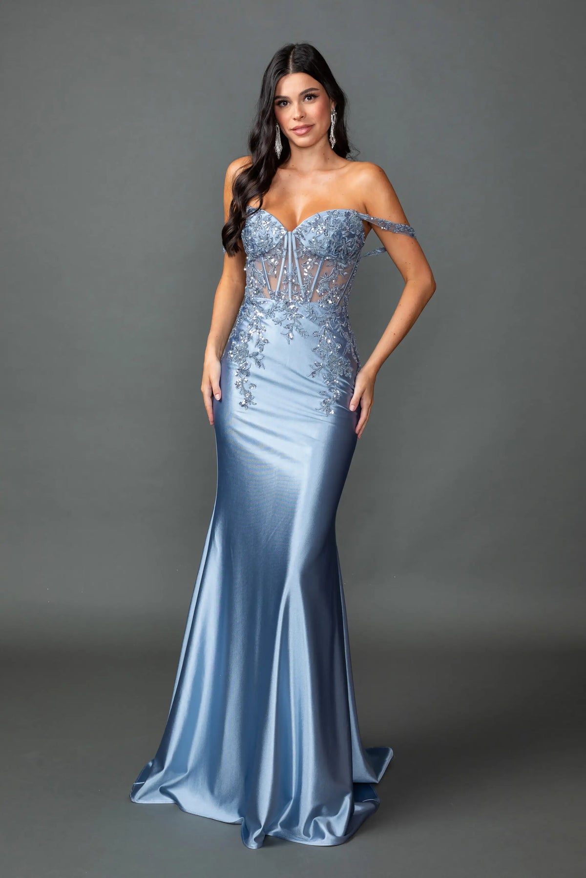 Showing beaded corset detailing above its satin skirt, this Dusty Blue prom dress is shown in full view.