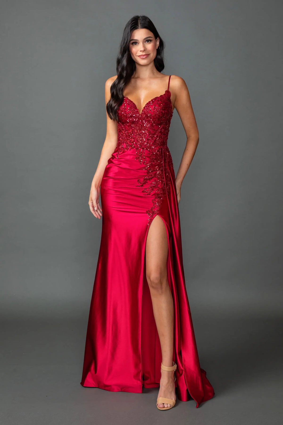 Showing sequin bodice detailing and a high slit, this Burgundy prom dress is shown in full view.