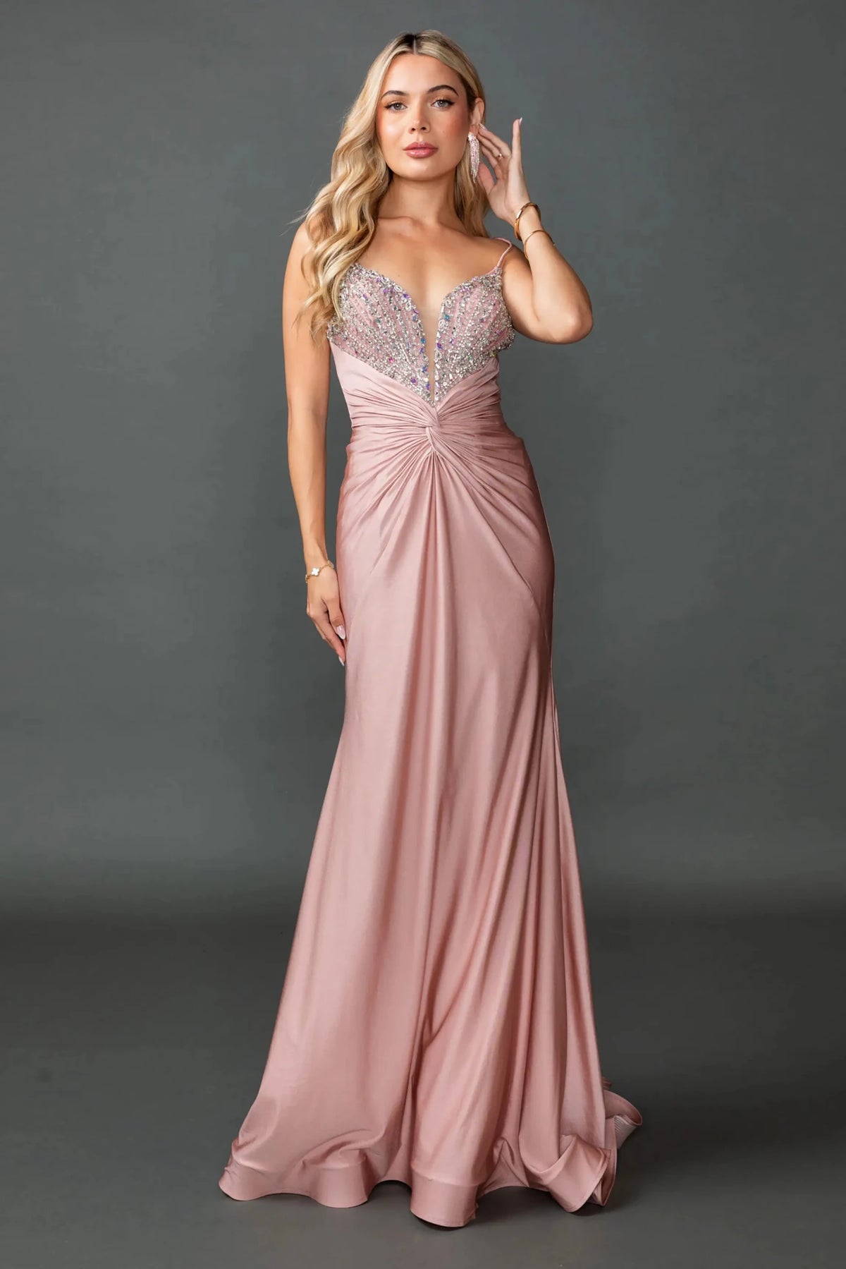 Showing a beaded V-neck bodice and ruched skirt, this Dusty Pink prom dress is shown in full view.