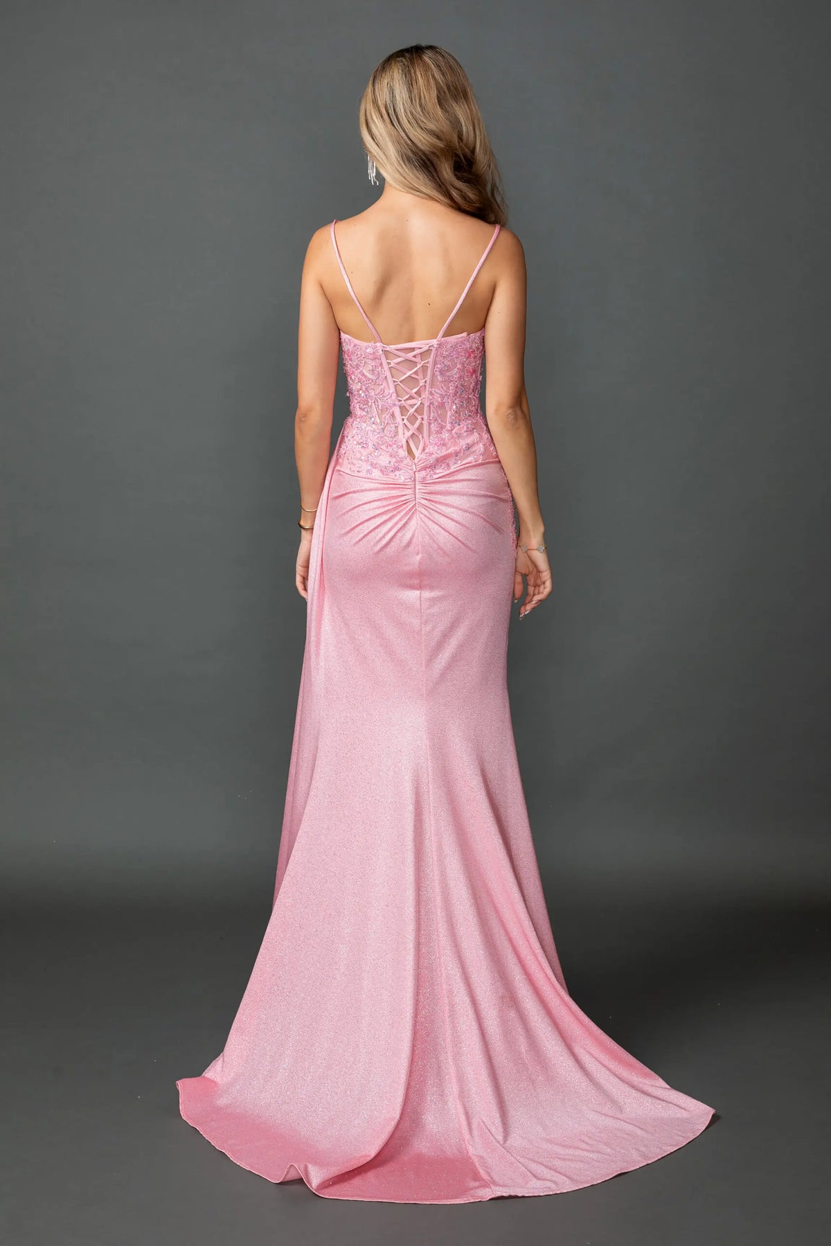 Revealing corset lacing above its fitted glitter skirt, this Pink prom dress is shown from the back.