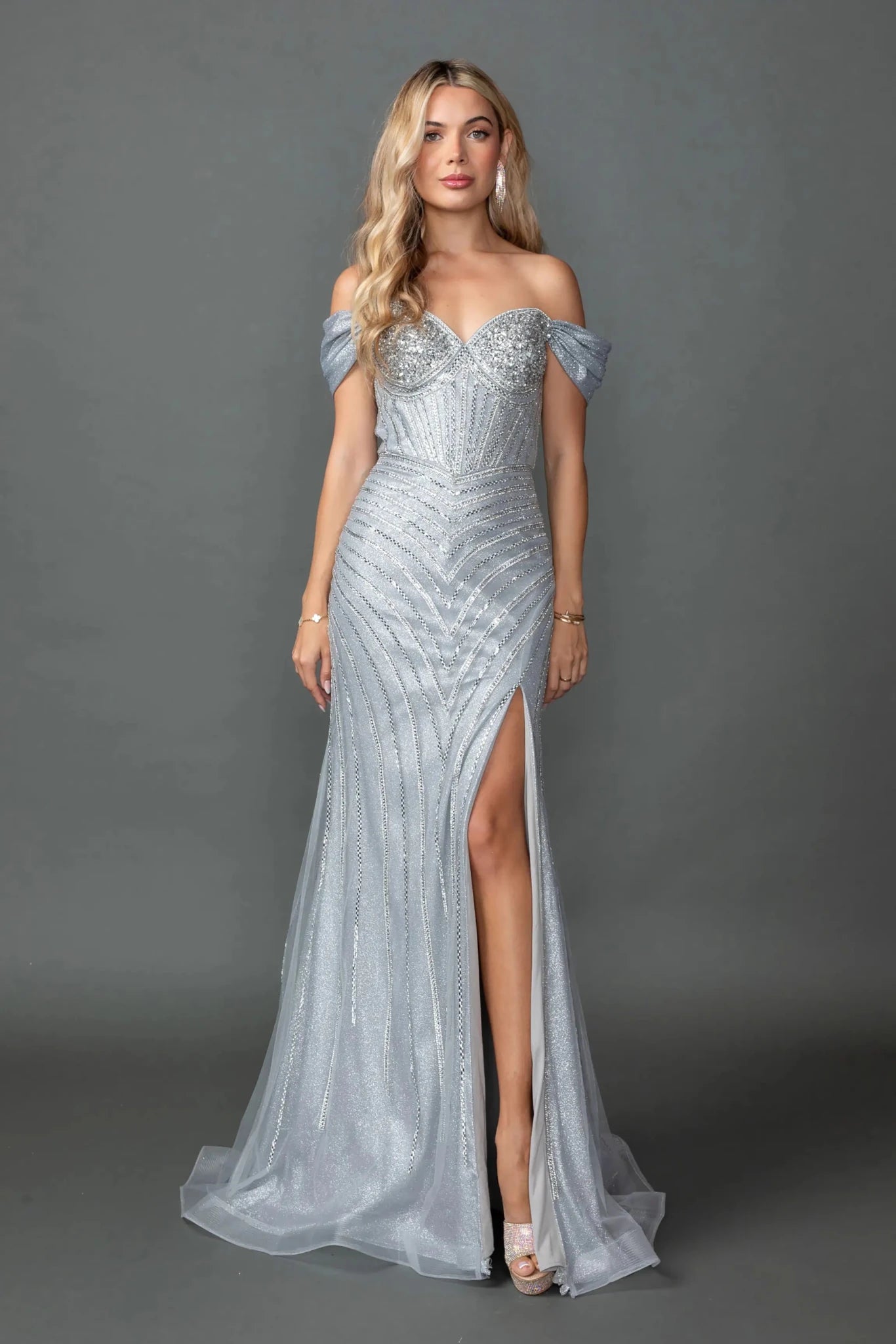 Woman in Silver off-shoulder prom dress with beaded corset and slit.