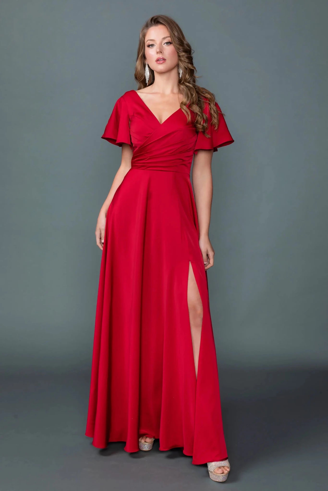 Woman in Burgundy V-neck prom dress with ruched bodice and slit A-line skirt.
