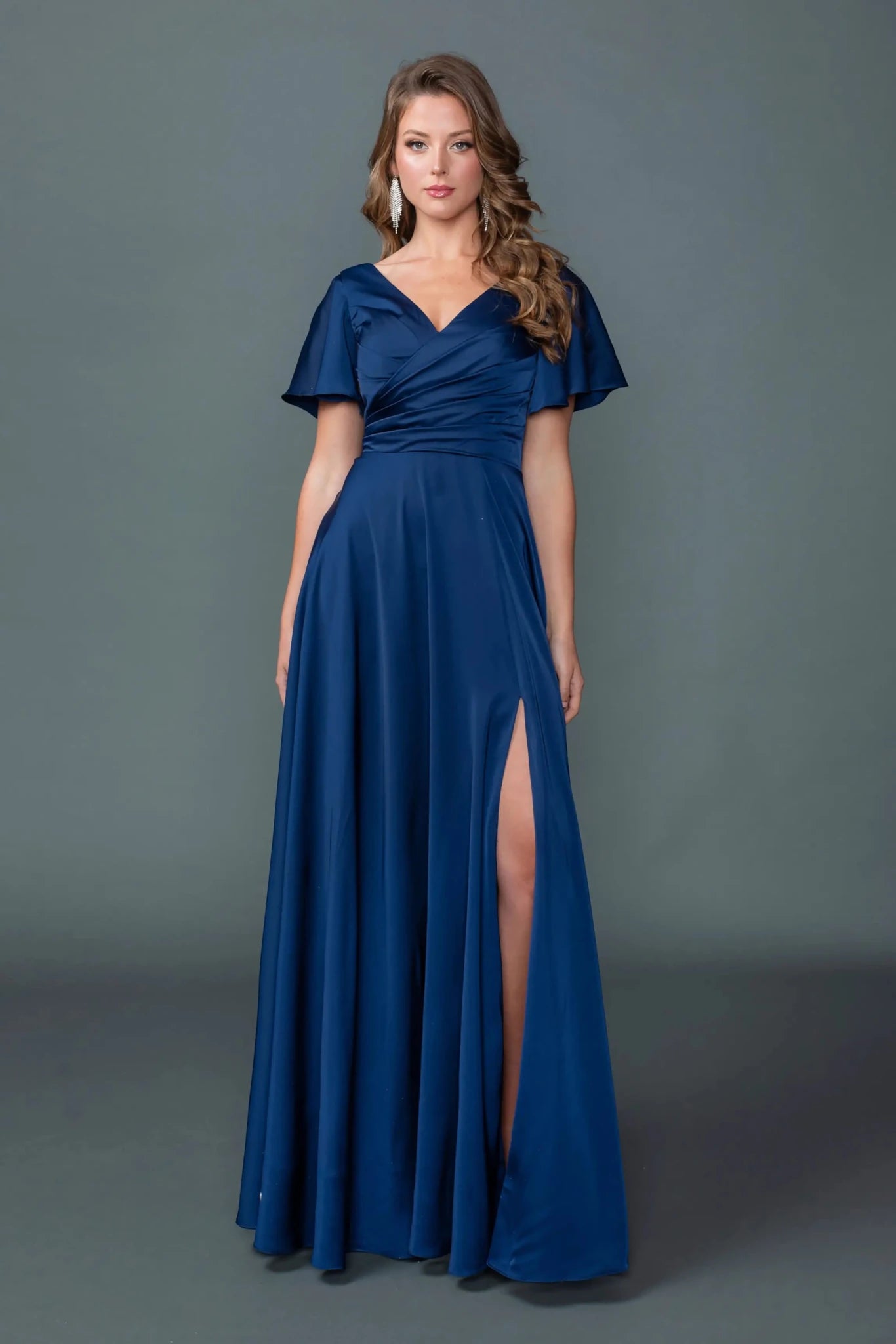 Woman in Navy V-neck prom dress with ruched bodice and slit A-line skirt.