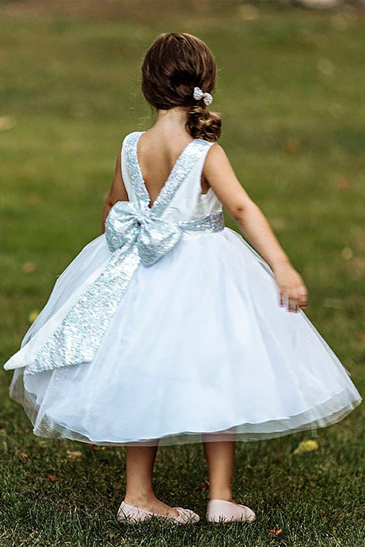 A white flower girl dress with a large bow.